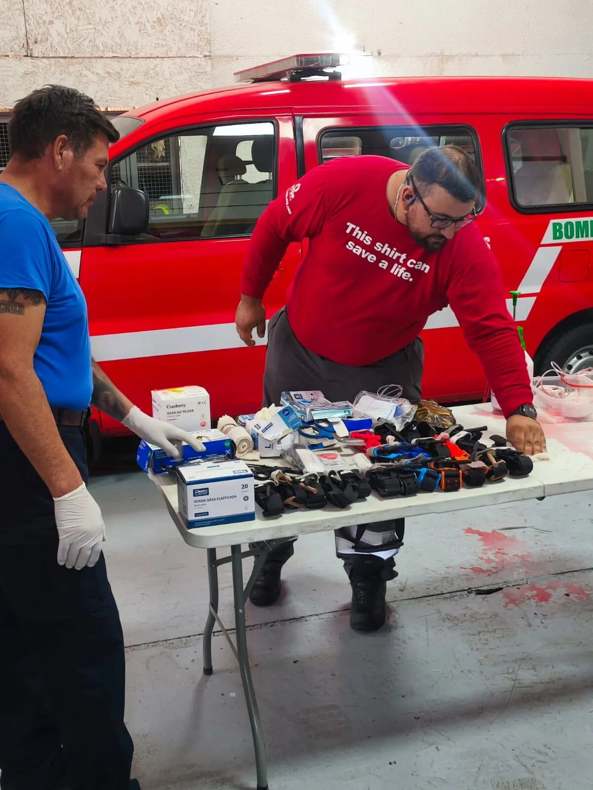 Instructor preparando insumos de trauma en una mesa junto a un carro de bomberos