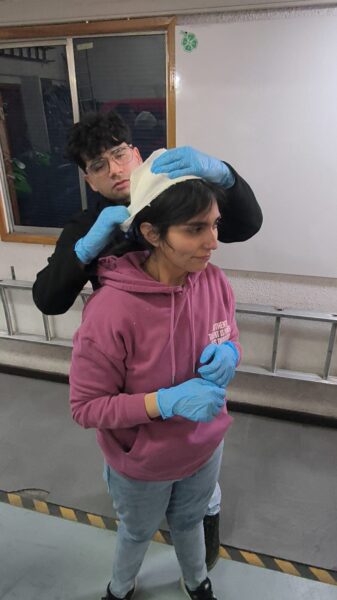 Alumno vendando la cabeza de una compañera durante la práctica